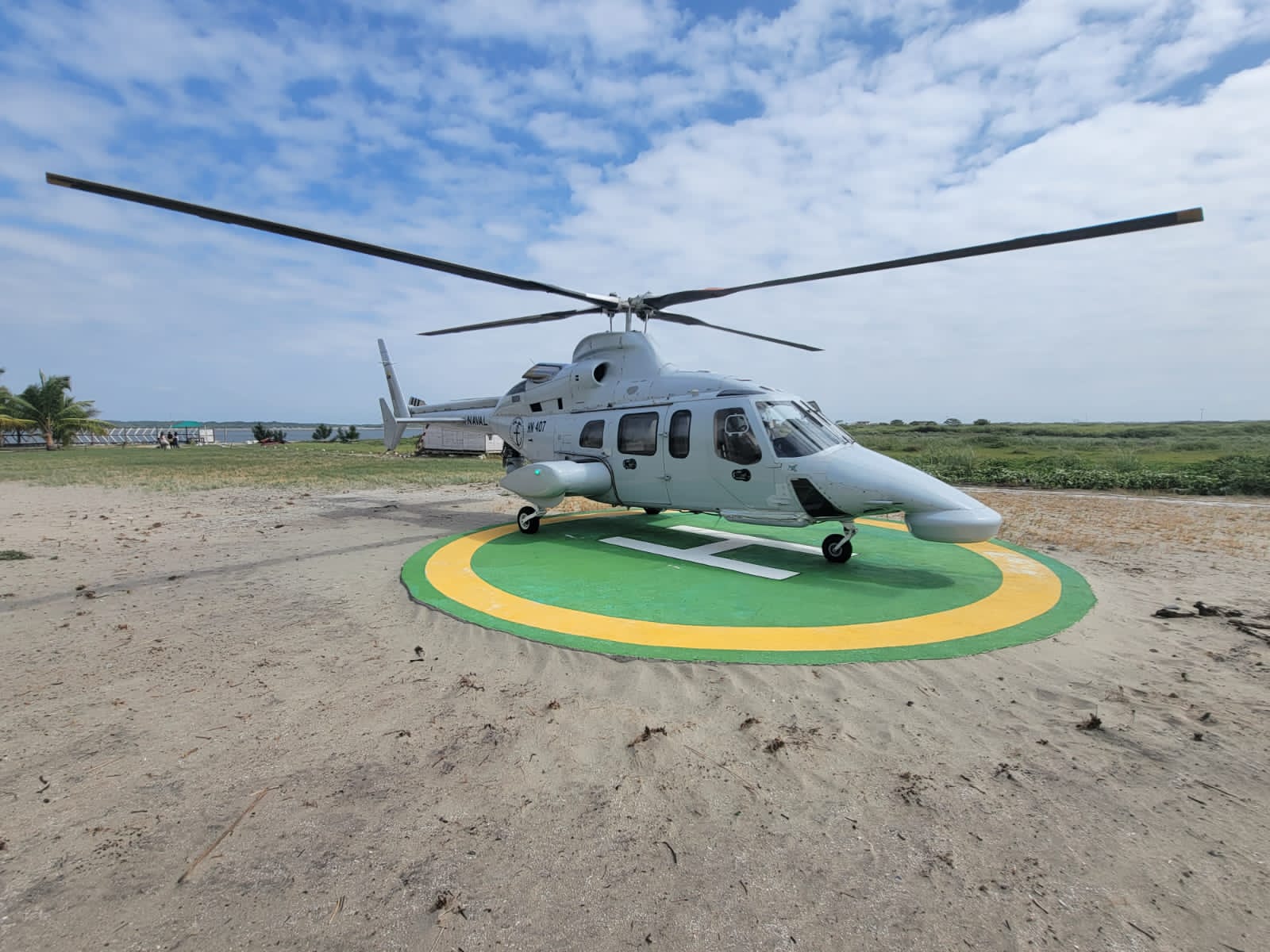 The Ecuadorian Navy's Bell 430 aircraft with the ID HN-407 is seen on a helipad in the middle of a sandy area. The helicopter is painted white, with 