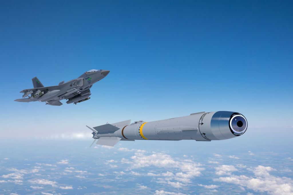 An artist's rendition of a KF-21 Boramae fighter jet flying above the clouds and firing off an IRIS-T missile. The jet plane, seen on the far left side of the image, is painted gray. The missile has a similar color scheme, seen jutting out white flames from its back as it propels itself forward. The background is a blue sky with white light clouds seen below.