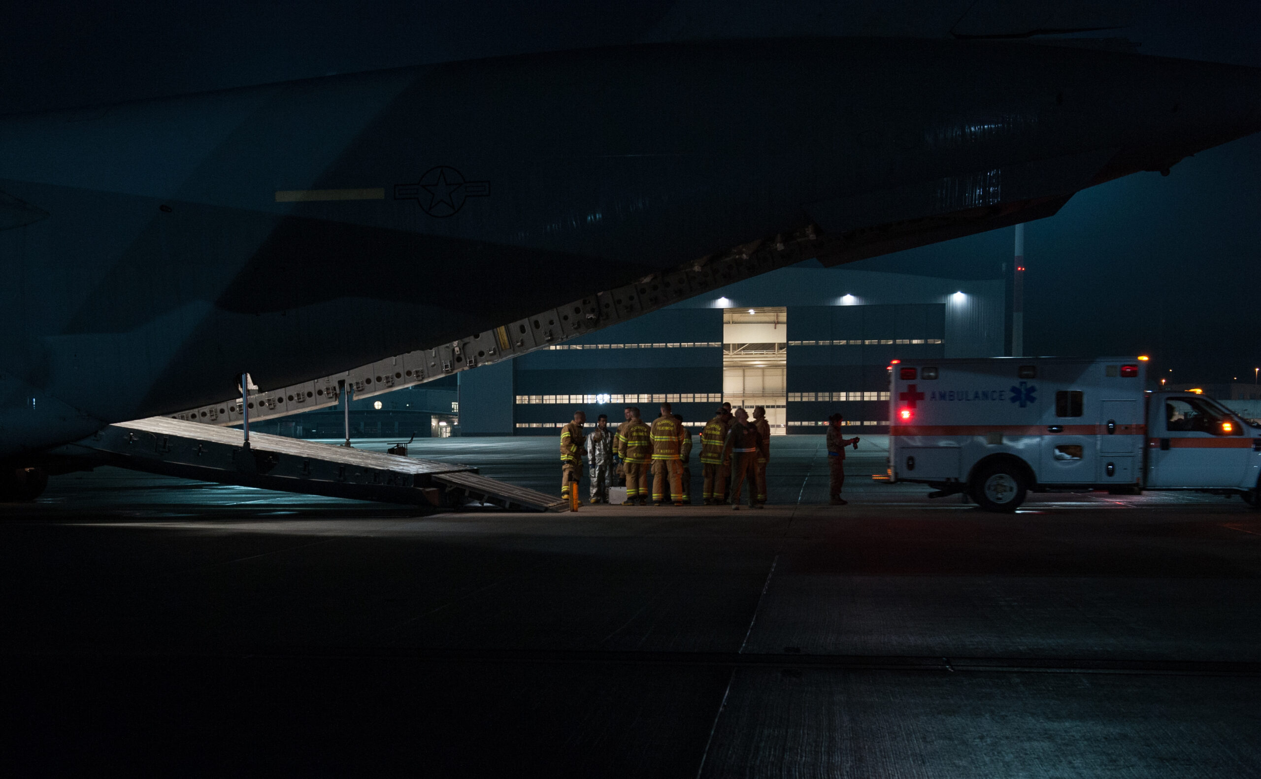 Firefighters from the 86th Civil Engineer Squadron Kaiserslautern Military Community Fire Emergency Services stand by after transporting a wounded warrior from a C-17 Globemaster III to an ambulance on Aug. 9, 2015, on Ramstein Air Base, Germany. Ramstein fire and medical personnel from the 10th Aeromedical Evacuation Operations Team and the 455th Critical Care Air Transport Team assisted with the aeromedical evacuation out of Afghanistan. (U.S. Air Force photo/Staff Sgt. Leslie Keopka)