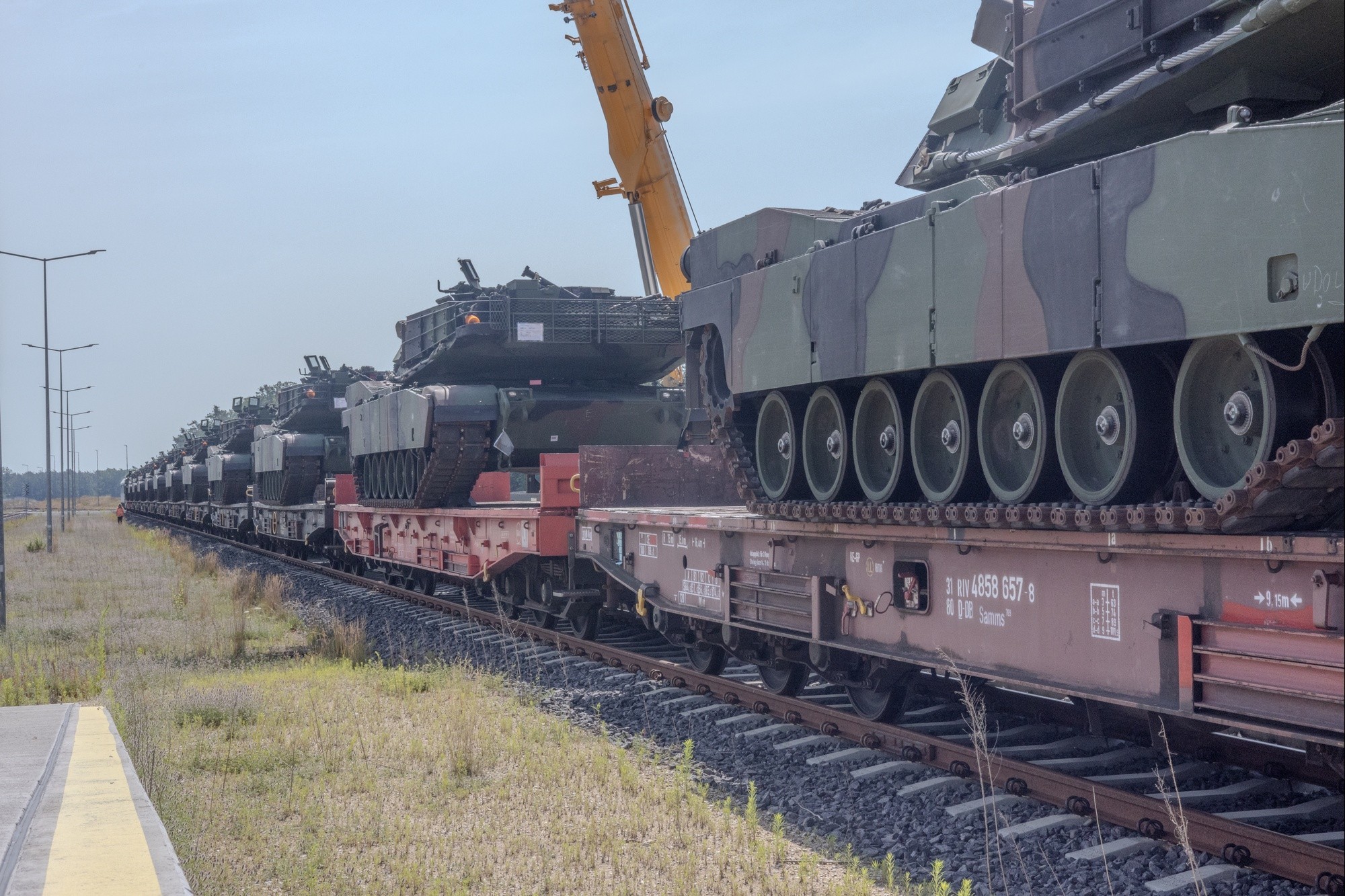 Multiple M1 Abrams tanks wait to be moved from a rail car to the staging area at the Powidz APS-2 Worksite, Powidz, Poland on June 27, 2024. The newly arrived vehicles and equipment will serve as a prepositioned stock for armored brigades deploying or training in the European region, specifically in Poland. (U.S. Army photo by Capt. Michael Mastrangelo)