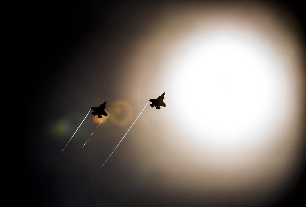 A pair of F-35 Lightning IIs pass under the sun while doing maneuvers to the Eglin Air Force Base runway