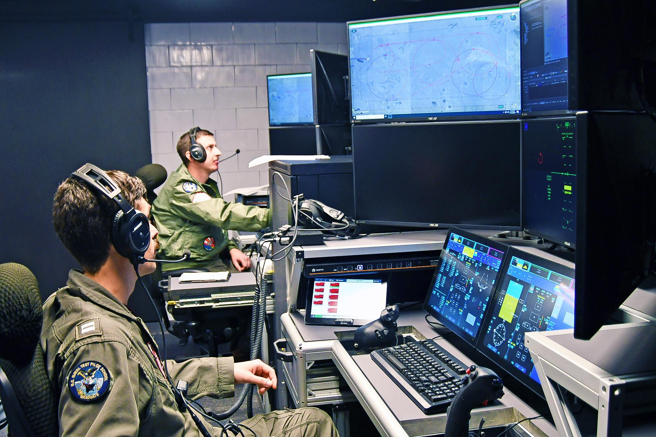 MQ-25 Air Vehicle Pilots Lt. Matt Pence (forward) and Lt. Steven Wilster, conduct test run to monitor the Unmanned Carrier Aviation Mission Control System ground control station, located at Naval Air Station Patuxent River, Md., as the system commands the General Atomics Aeronautical Systems, Inc. (GA-ASI) MQ-20 Avenger surrogate, located at the company’s test facility in California, in preparation for demonstration event in November 2024. (U.S. Navy photo)