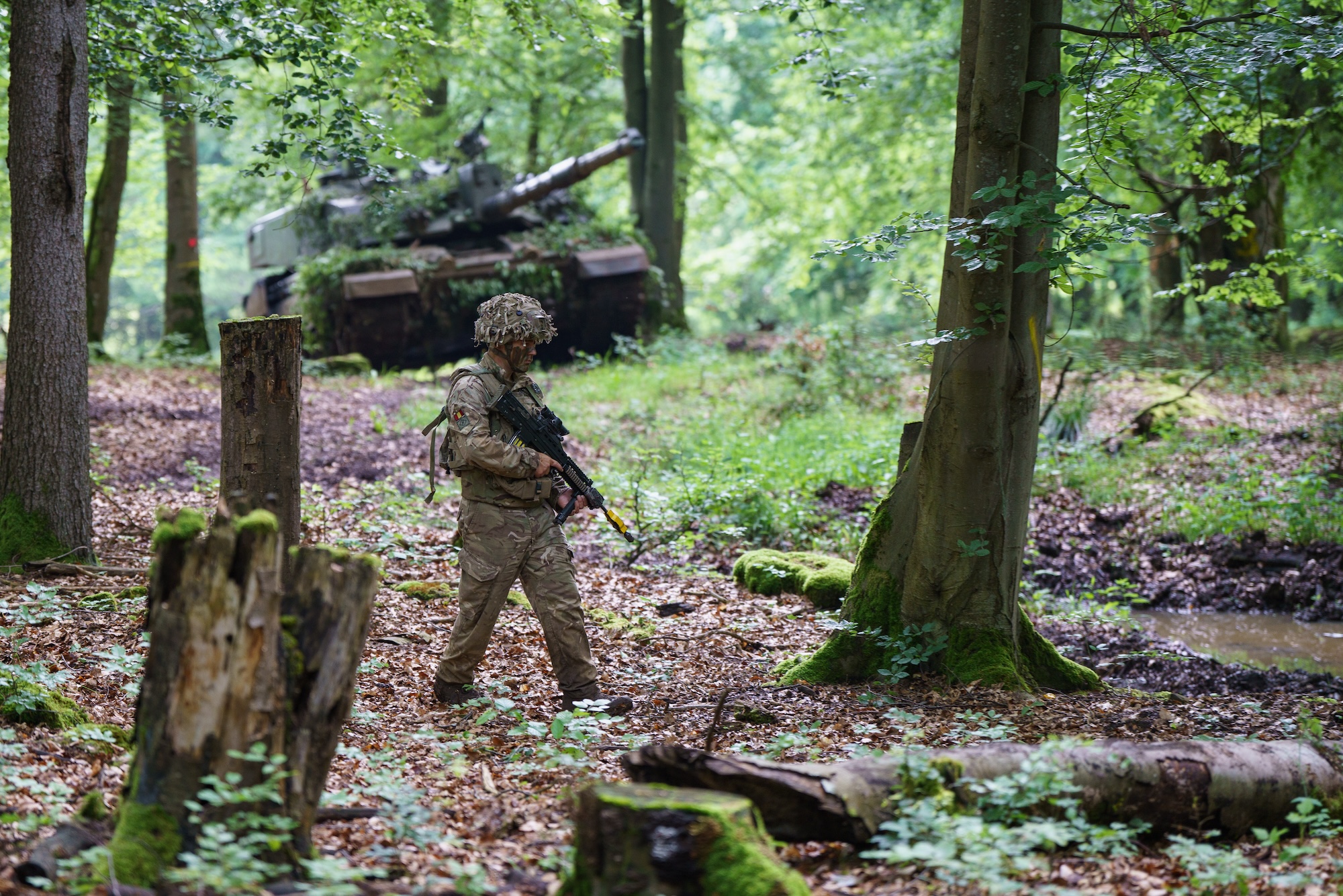 UK soldier patrolling the immediate area surrounding a command post, with a KRH Challenger 2 and its crew waiting nearby