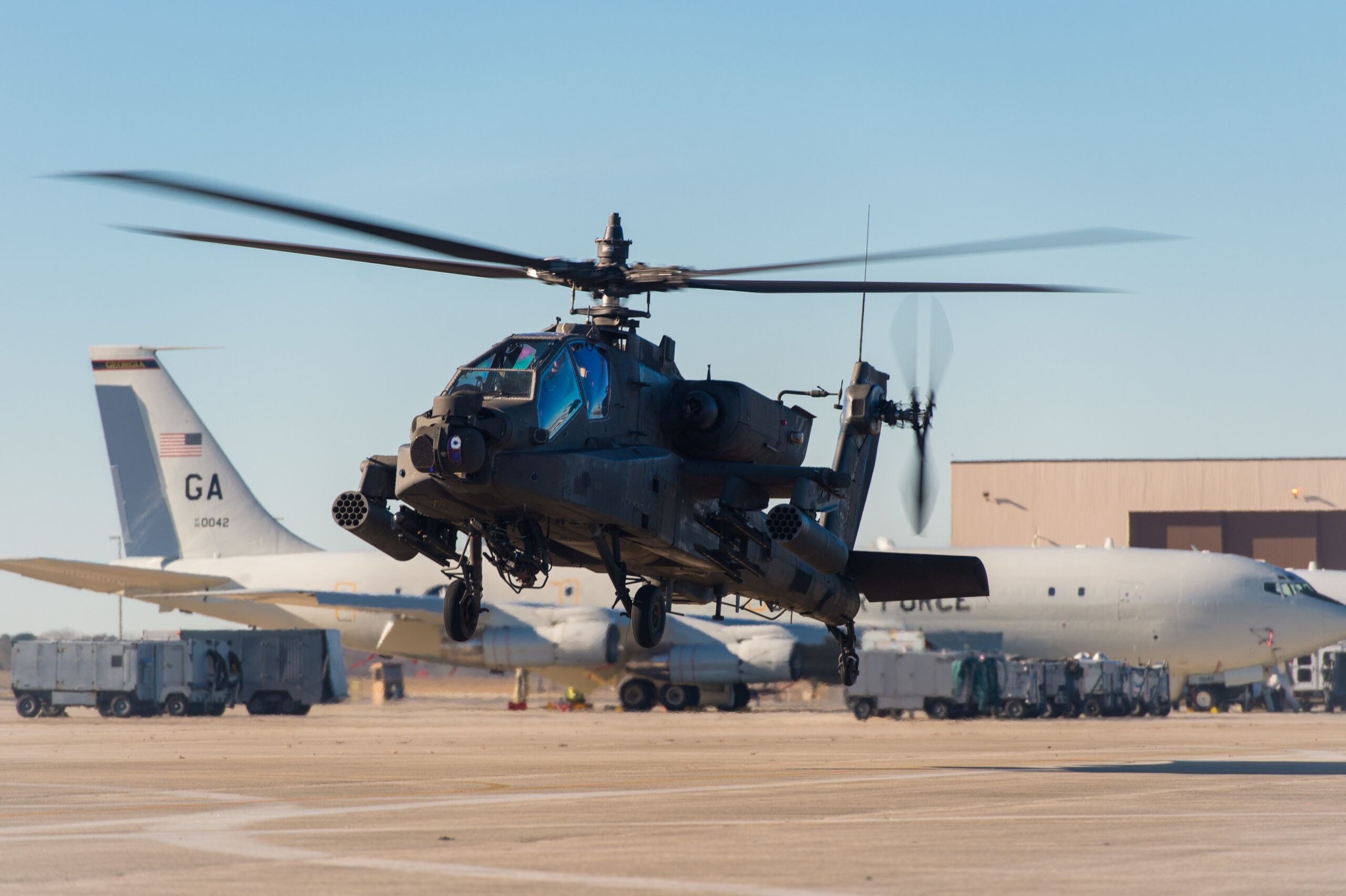 An AH-64D Apache helicopter hovers beside E-8C Joint STARS aircraft prior to departing Robins Air Force Base (AFB), Ga., Jan. 10, 2019. U.S. Army Chief Warrant Officer 2 William Klinger, pilot in command, and Chief Warrant Officer 2 Andrew Williamson, pilot, from the 3rd Infantry Division, 3rd Combat Aviation Brigade, 3/17 Cavalry Regiment, Hunter Army Airfield, Ga., flew the helicopter to Robins AFB to meet with Soldiers and Airmen from Team JSTARS to brief them on the capabilities of the AH-64D Apache and learn more about the capabilities of the E-8C Joint STARS. (U.S. Air National Guard photo by Senior Master Sgt. Roger Parsons)