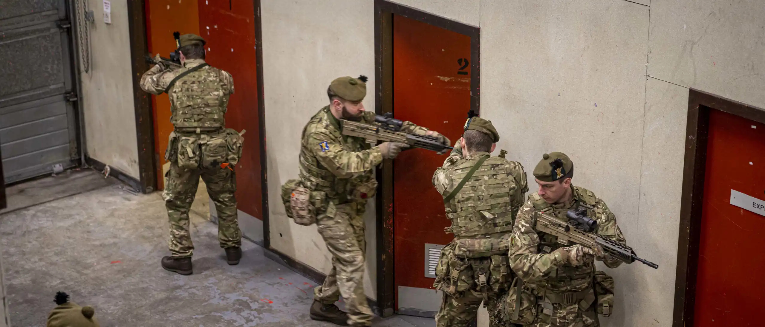 Army reservists prepare to enter a room during an exercise at a new Army training facility. The simulation facility in Scotland creates realistic training for Army reservists. The creation and development of a new Army training facility in Dundee saw Reservists from the 7th Battalion, The Royal Regiment of Scotland (7 SCOTS) train in using simulated ammunition. The new facility, located in Oliver Barracks in Dundee, allows urban operations training. It was constructed and designed for the use of simulation to create a realistic environment for soldiers to enhance their infantry skills in advance of deployments in the UK and overseas. 7 SCOTS, although a light role (Reserve) battalion based in Perth are commanded by 19th Light Brigade who form part of 1st (United Kingdom) Division. Training at weekends highlights the immense level of discipline and commitment by reservists within 7 SCOTS; juggling their civilian routine and employment to participate – gaining and enhancing transferable employable skills. Reservists bring specialist civilian capabilities that are essential both on and off the battlefield, while gaining transferable qualifications by training with the Army. The roles and tasks demanded of the Army Reserve continue to evolve, with more opportunities to enjoy the challenges that come with being a Reservist both in the UK and worldwide.