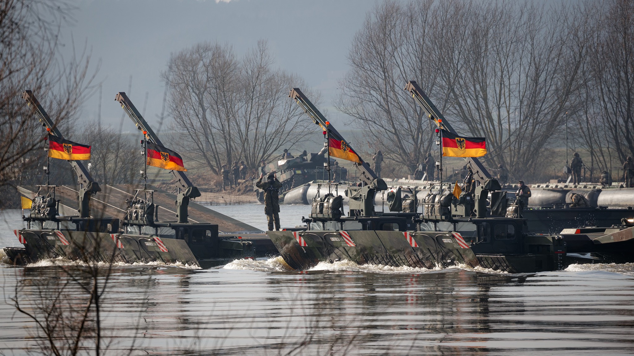 Soldaten vom Deutsch/Britischen Pionierbrückenbataillon 130 setzen mit der Schwimmschnellbrücke Amphibie M3 im Fährbetrieb die Fahrzeuge des multinationalen Gefechtsverbandes über die Weichsel bei der Übung Dragon in Korzeniewo/Polen im Rahmen der Übungsserie Quadriga 2024, am 03.03.2024.