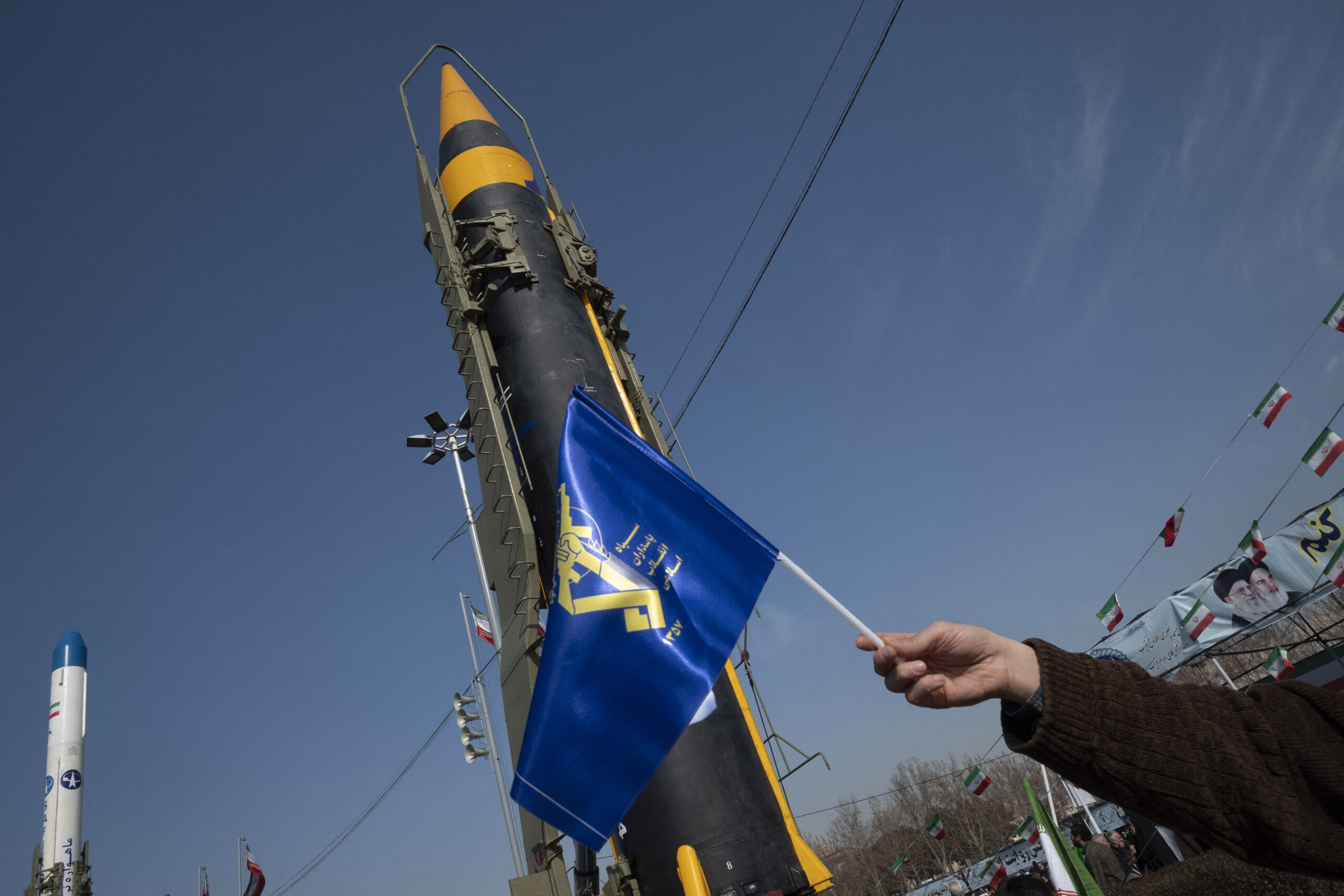 A man is waving a flag of the Islamic Revolutionary Guard Corps (IRGC) in front of the Iranian-made Kheibar Surface-to-Surface missile at Azadi (Freedom) Square in western Tehran, Iran, on February 11, 2024, during a rally to mark the 45th anniversary of the victory of Iran's 1979 Islamic Revolution. The Iranian Islamic Revolution, which led to the overthrow of the Pahlavi dynasty in 1979, replaced the Imperial State of Iran with the present-day Islamic Republic of Iran. (Photo by Morteza Nikoubazl/NurPhoto) (Photo by Morteza Nikoubazl / NurPhoto / NurPhoto via AFP)