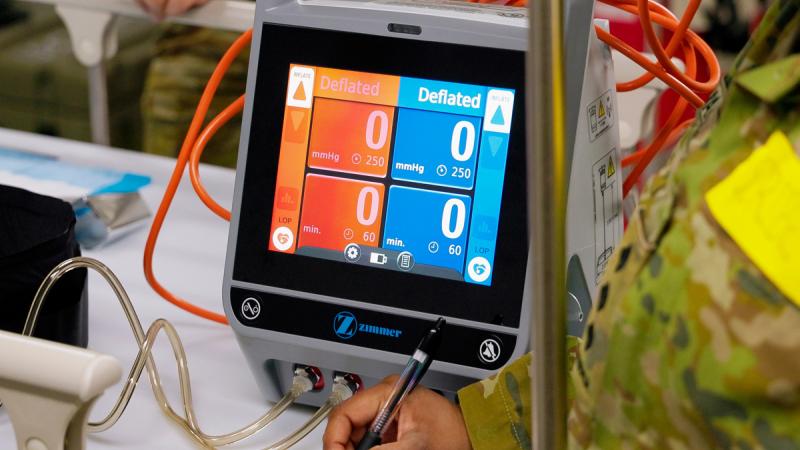 A medical equipment with a built-in screen that shows multiple values on the screen. Some of it appears to be measuring blood pressure. Its display is colored orange on the left and blue on the rigth, with both sides displaying the word 