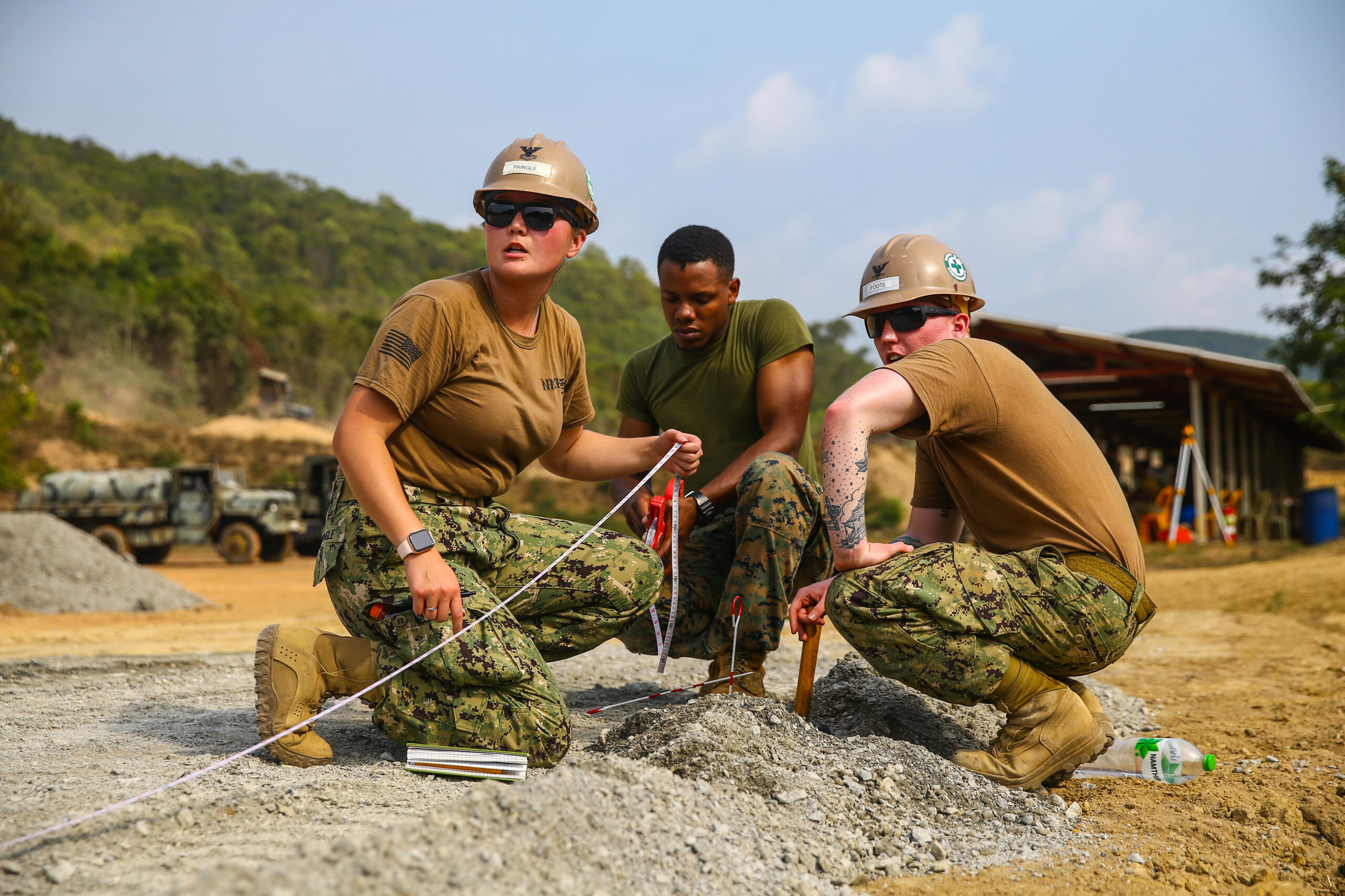 U.S. service members Petty Officer 2nd Class Megan Pringle, left, 3rd Class Jonah Foote, right, and Sgt. Emmet Marbury relay the new road measurements on Royal Thai Marine Base Sattahip, Kingdom of Thailand, Jan. 11, 2020. U.S service members and Royal Thai Marines worked together during a U.S. and Thai subject matter expert exchange to share best practices, increase their ability to work together and build friendships. Pringle, a native of Lacey, Washington, is the lead builder with Naval Mobile Construction Battalion 5. Foote, a native of Gaylord, Michigan, is a steelworker with NMCB 5. Marbury, a native of Dallas, Texas, is the 3rd squad leader with Bravo Company, 9th Engineer Support Battalion, 3rd Marine Logistics Group. (U.S. Marine Corps photo by Cpl. Ryan Harvey)