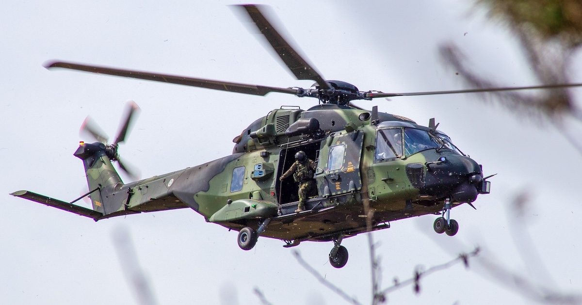 A soldier coming out of a Finnish NH90 helicopter flying mid-air