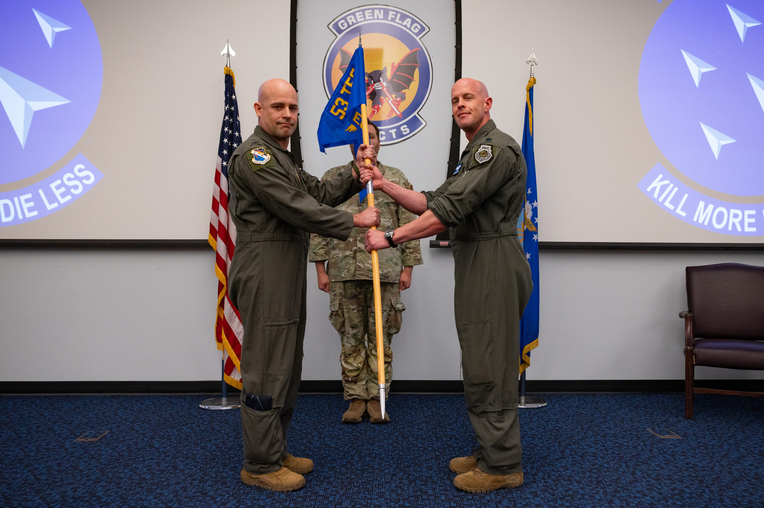 U.S. Air Force Col. Joshua M. Biedermann, left, 53rd Test and Evaluation Group commander, passes the unit guidon to Lt. Col. Matthew W. Jensen, inaugural commander of the Experimental Operations Unit (EOU), during the EOU activation ceremony at Nellis Air Force Base, Nevada, June 5, 2025. The transfer of the guidon formally established the new unit under Jensen’s leadership. (U.S. Air Force photo by Airman 1st Class Michael Sanders)