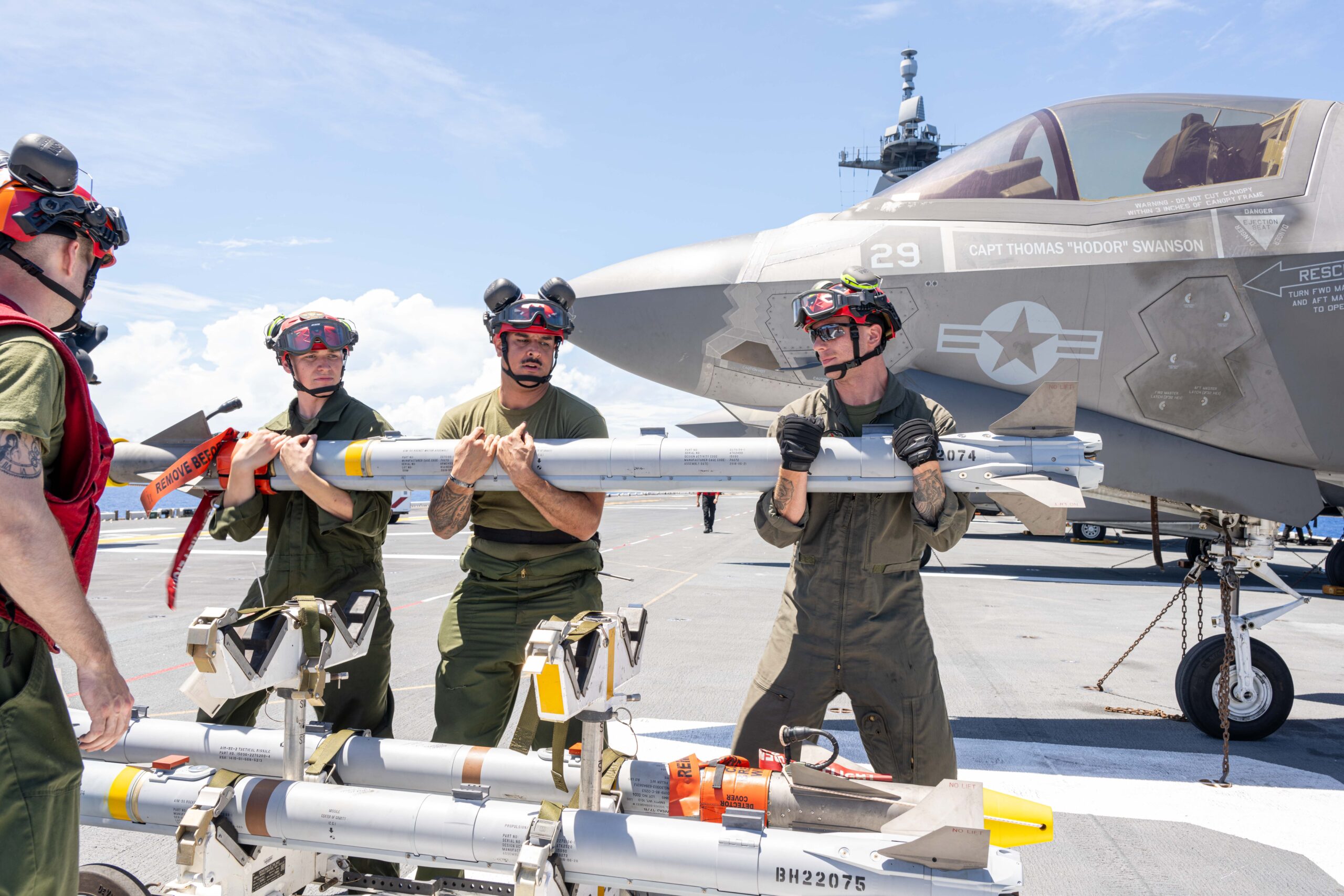 250603-N-FC892-1158 PHILIPPINE SEA (June 3, 2025) Marines, assigned to the 31st Marine Expeditionary Unit (MEU), prepare to load an AIM-9X missile on the flight deck of the forward-deployed amphibious assault ship USS America (LHA 6) while in the Philippine Sea, June 3. America, lead ship of the America Amphibious Ready Group, is operating in the U.S. 7th Fleet area of operations. U.S. 7th Fleet is the U.S. Navy’s largest forward-deployed numbered fleet, and routinely interacts and operates with allies and partners in preserving a free and open Indo-Pacific region. (U.S. Navy photo by Mass Communication Specialist 2nd Class Cole Pursley)