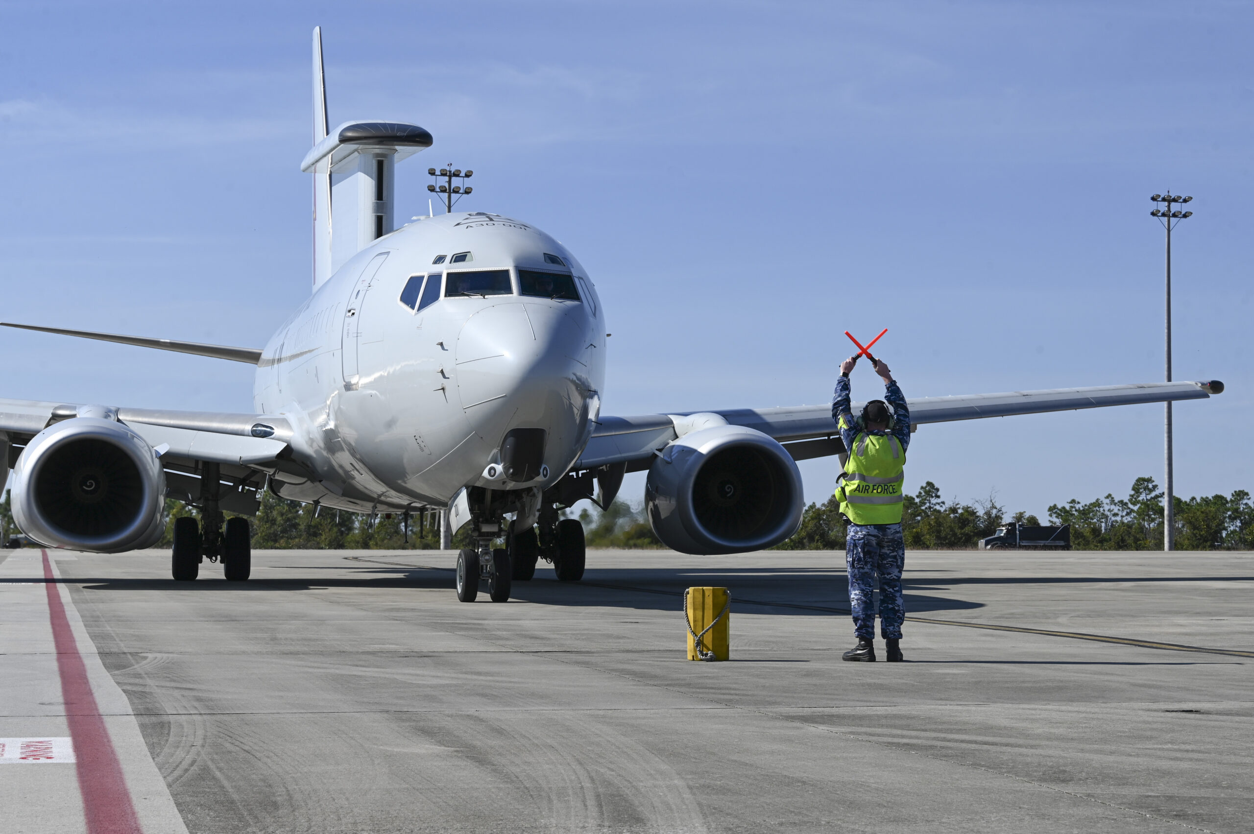 A Royal Australian air force maintainer signals to an E-7 Wedgetail to stop after reaching its parking area after completing a scenario during Checkered Flag 24-1 at Tyndall Air Force Base, Florida, Nov. 1, 2023. Checkered Flag is a large-force aerial exercise held at Tyndall Air Force Base which fosters readiness and interoperability through the incorporation of 4th and 5th-generation aircraft during air-to-air combat training. (U.S. Air Force photo by Staff Sgt. Jake Carter)