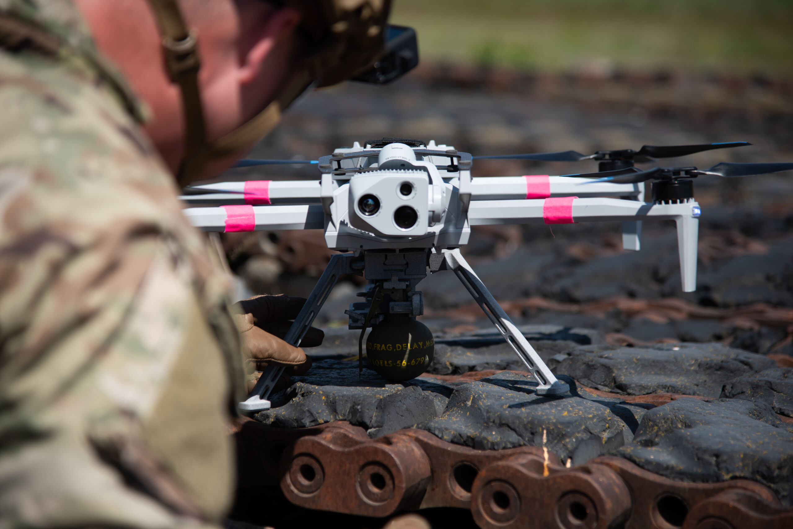 U.S. Army 1st Lt. David Baker, an electronic warfare officer for the 278th Armored Cavalry Regiment, prepares a M67 grenade for a Skydio X10 in the Grafenwoehr Training Area, Germany, June 25, 2025. Soldiers from 7th Army Training Command, the Joint Multinational Training Group-Ukraine and 173rd Airborne Brigade all worked together to make this the first live grenade drop from a unmanned aircraft system in the U.S. Army for conventional forces. This drop of a live M67 grenade used a Skydio X10 and a U.S. Army Combat Capabilities Development Command-developed Audible dropper for the first time.. (U.S. Army photo by Sgt. Collin Mackall)