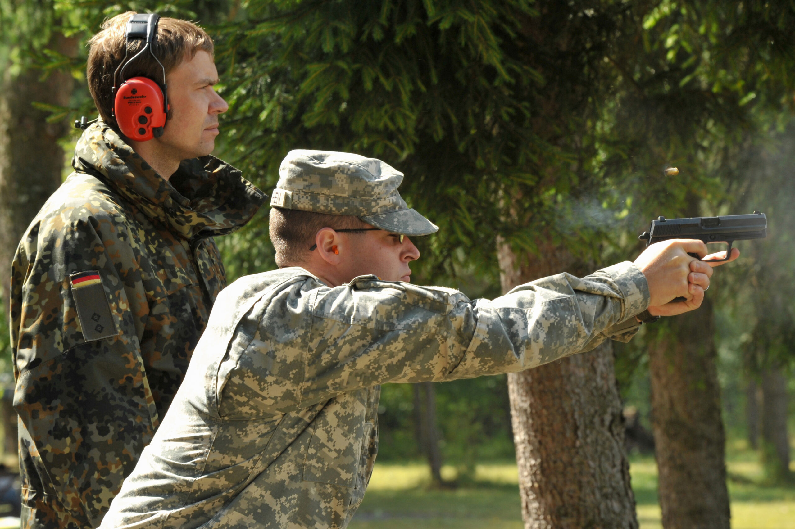 U.S. Army Spc. Andrew Maclaren, assigned to U.S. Garrison Grafenwoehr, fires the German P8 pistol under the guidance of German Army Oberleutnant Kay Schwotzer during the qualification for the Schuetzenschnur, the German Armed Forces Badge of Weapon's Proficiency, at the 7th Army Joint Multinational Training Command's Grafenwoehr Training Area, Germany, July 30, 2013. (U.S. Army photo by Visual Information Specialist Markus Rauchenberger/released)