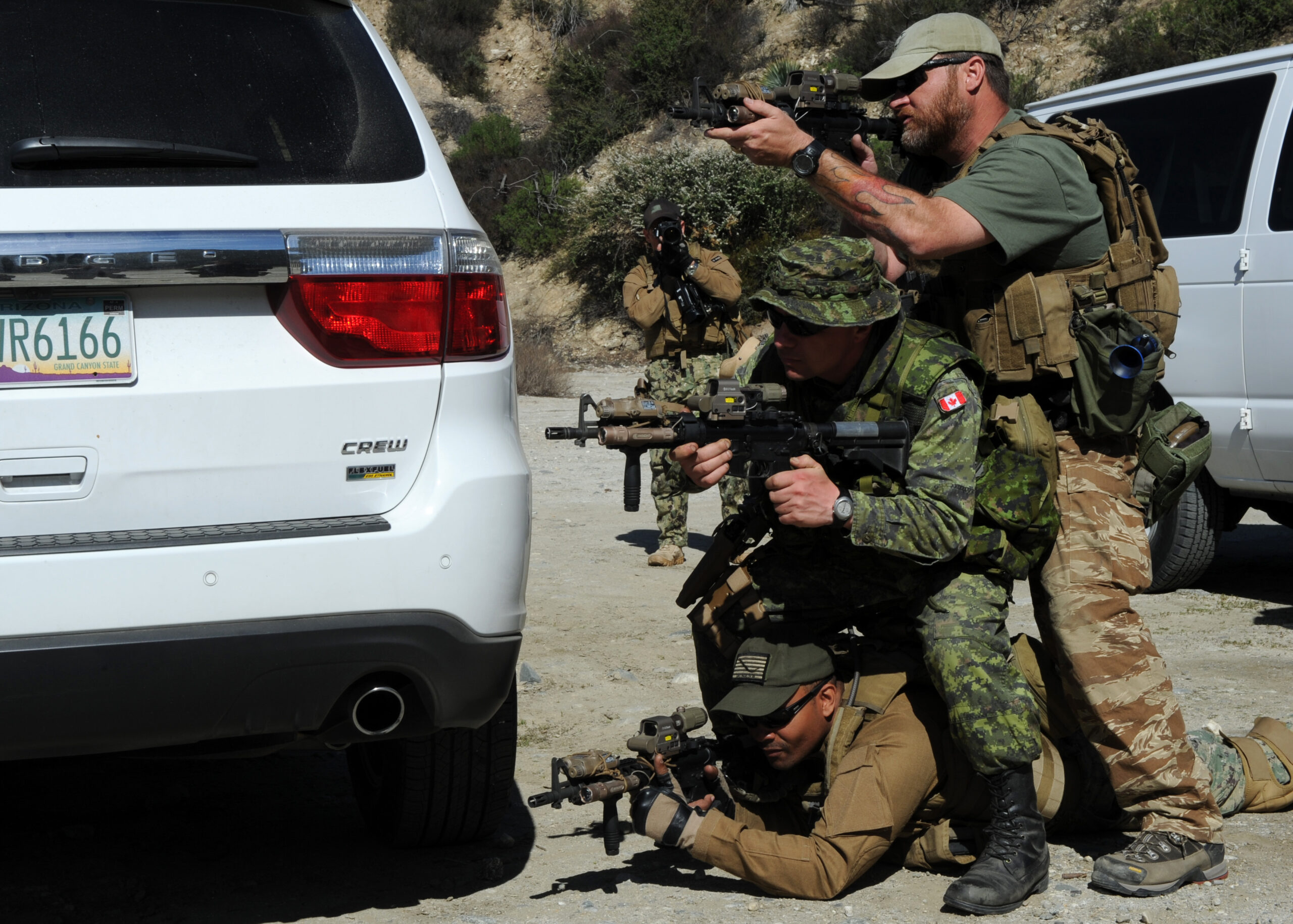Shawn Lewis, a Tactical Firearms Training Team instructor, top, Canadian armed forces Master Cpl. Patrick Blanchard (center), and Mass Communication Specialist 1st Class Peter Lewis practice returning fire during a convoy ambush as part of Fleet Combat Camera Pacific's Winter Quick Shot 2013 combined field-training exercise in the Angeles National Forest near Azusa, Calif., Feb. 15. Quick Shot is a semi-annual exercise that improves combat camera service members' ability to operate in a tactical environment. (U.S. Navy photo by Mass Communication Specialist 1st Class Mike Lenart/Released)