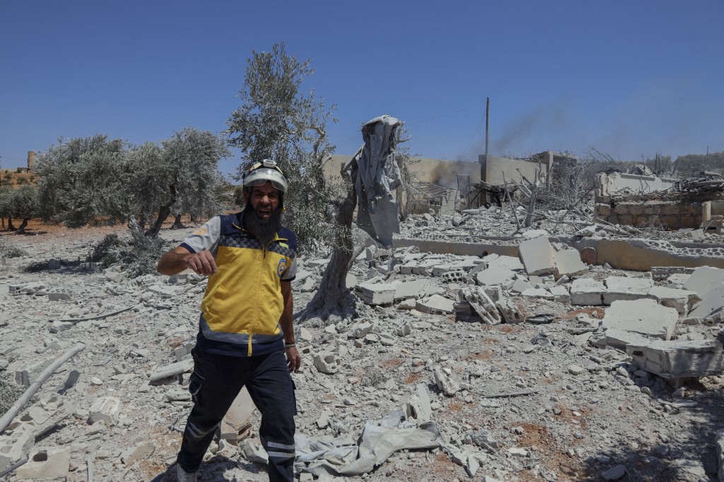 A rescue worker walking over the rubble of a destroyed building in Syria