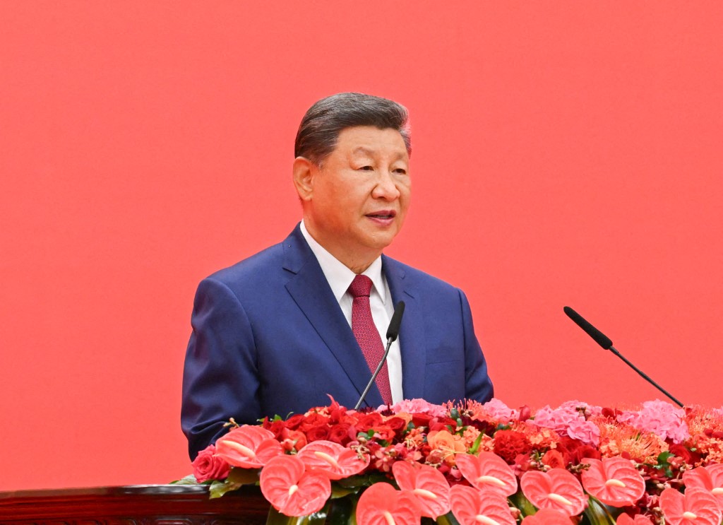 Chinese President Xi Jinping in front of a red background at a commemoration event