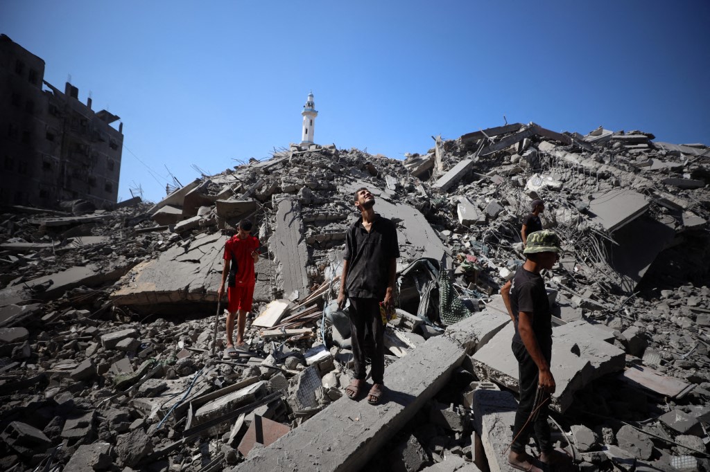 Palestinians walking over rubble of fallen building in Gaza