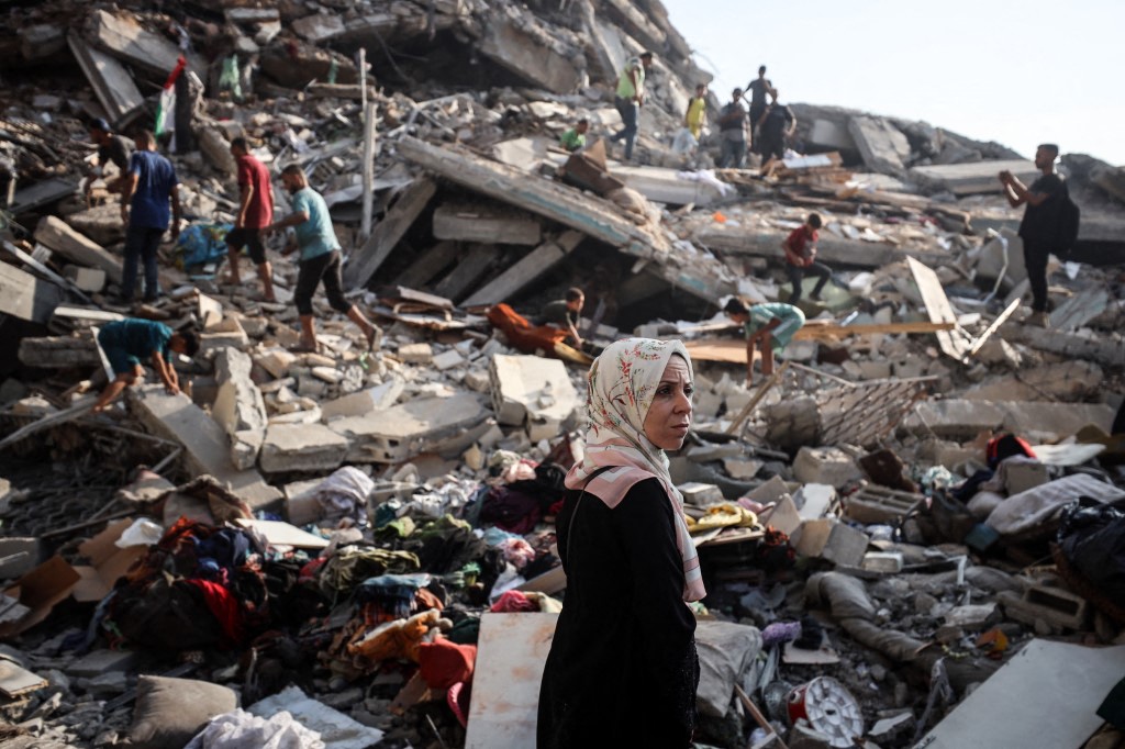 Palestinian residents walking over building rubble after an Israeli strike