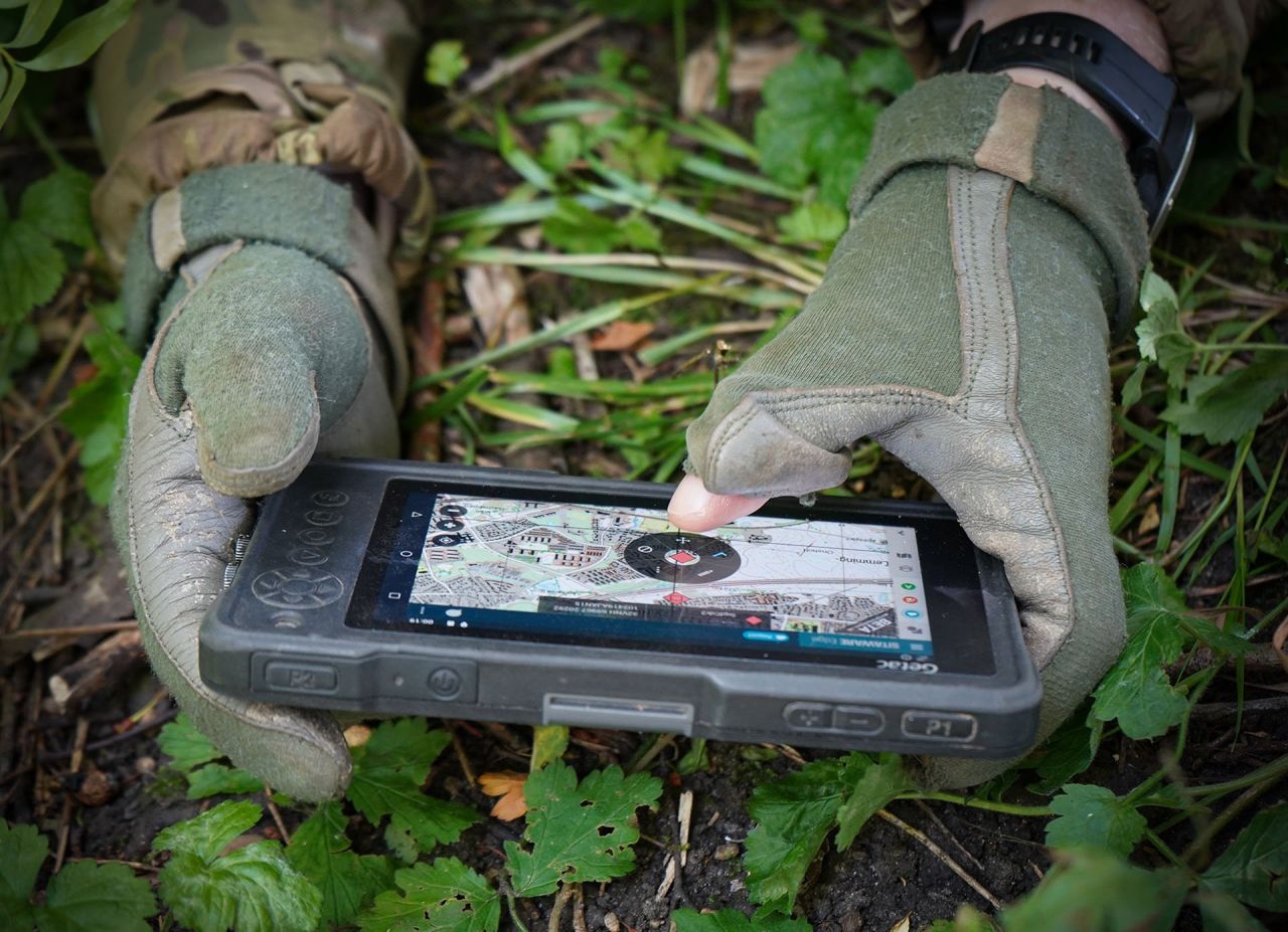 A soldier is using the SitaWare device on the field