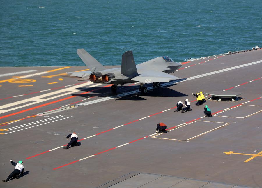 A J-35 fighter jet taking off from the Fujian aircraft carrier while staff are crouched