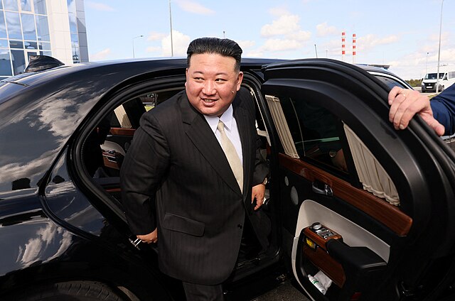 North Korean leader Kim Jon Un exiting a black limousine while wearing a black suit