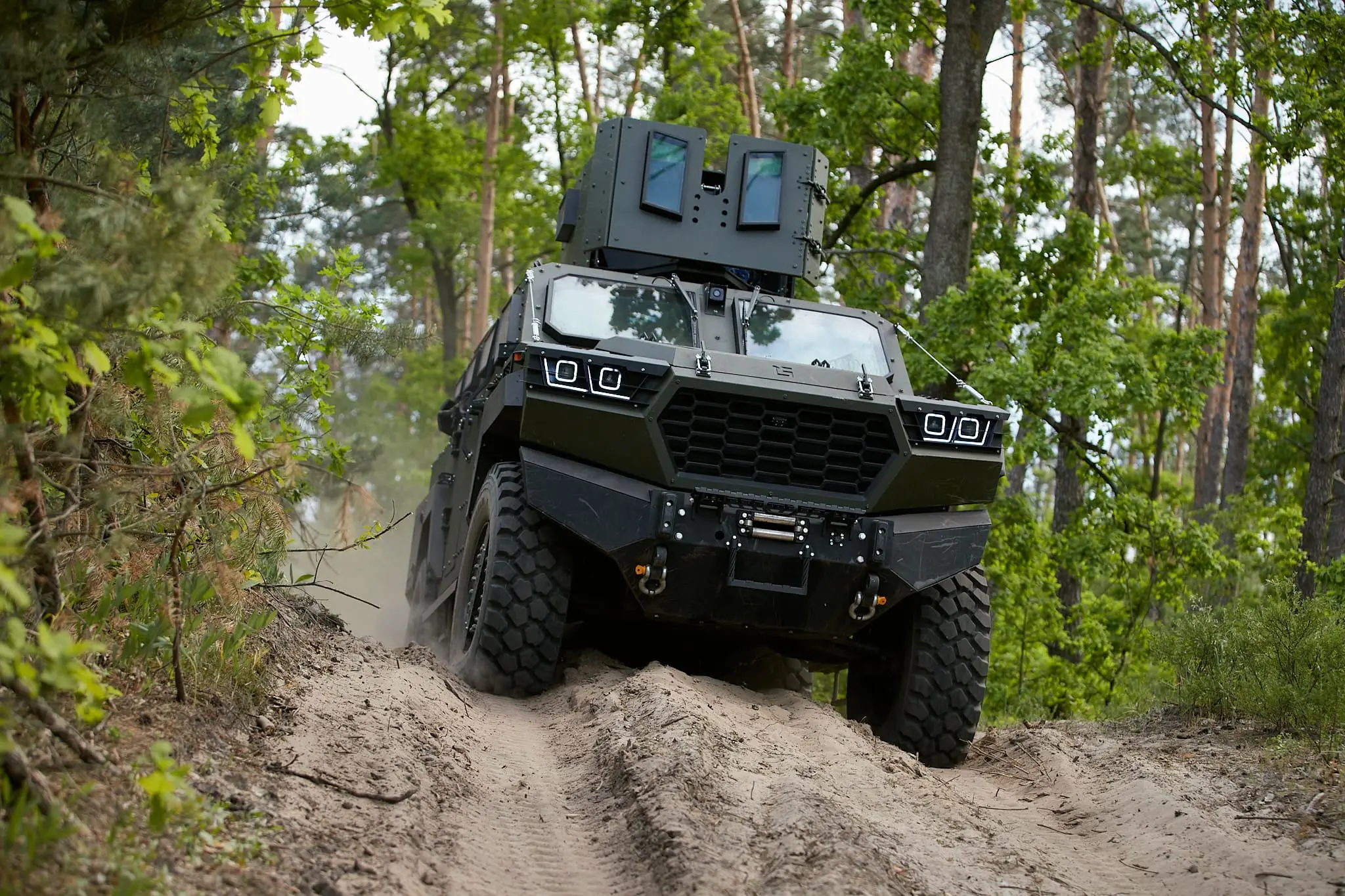 The Inguar-3 armored vehicle driving through a soil pathway with a forest background