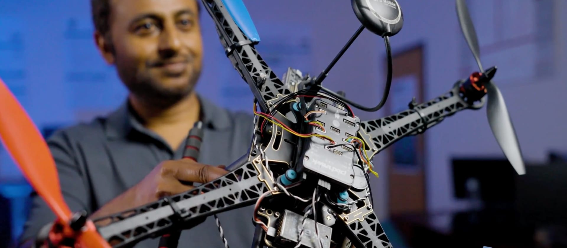 A researcher holding the SHIELD drone inside a dim room