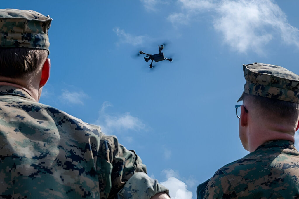US Marines looking at a drone flying in the air with a sunny background