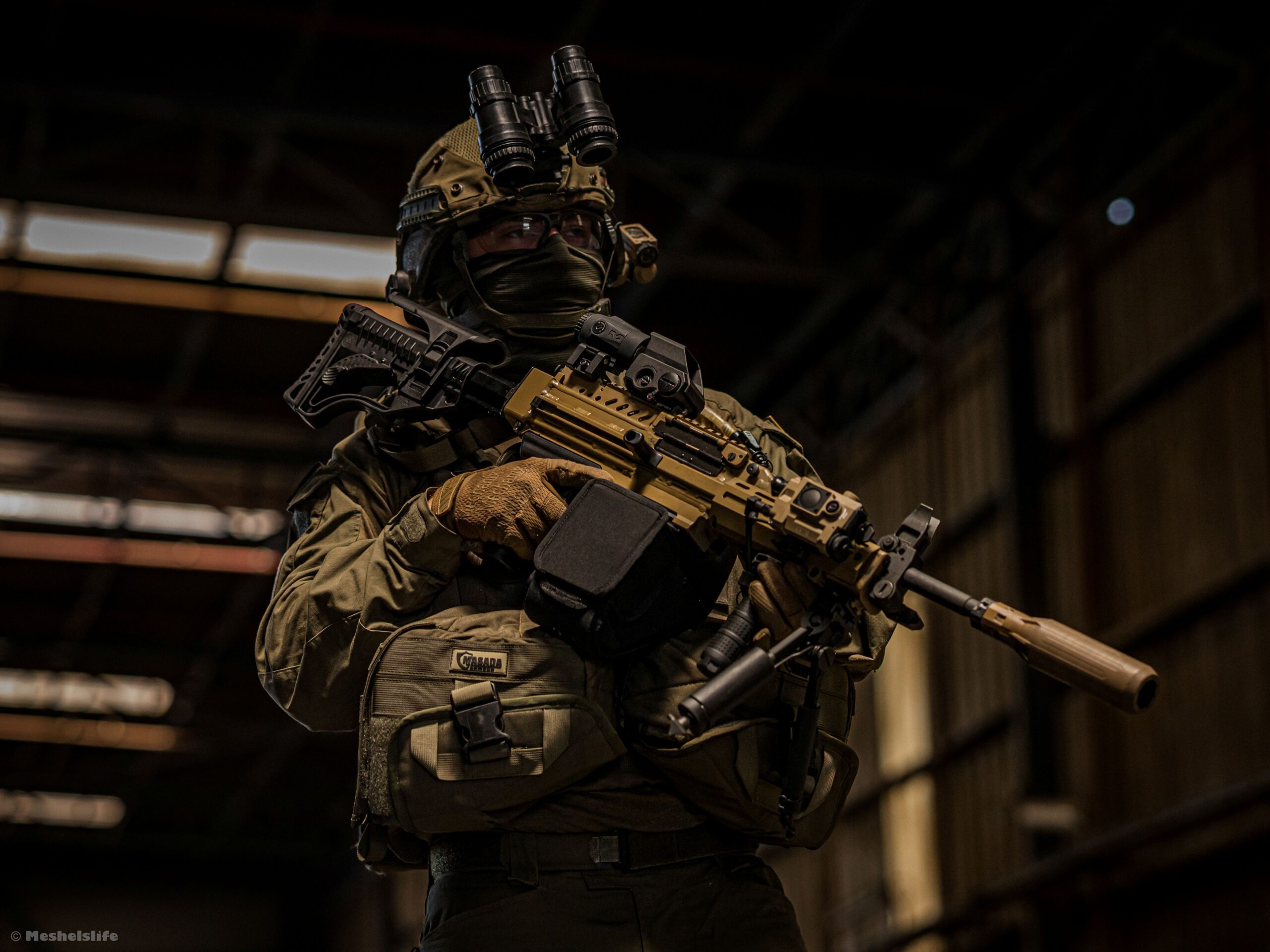 Soldier holding rifle with 3D-printed suppressor.