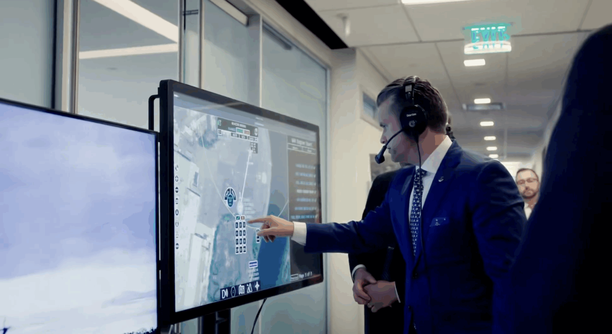 Pete Hegseth interacts with a touchscreen command-and-control system displaying real-time aerial surveillance data during a demonstration.