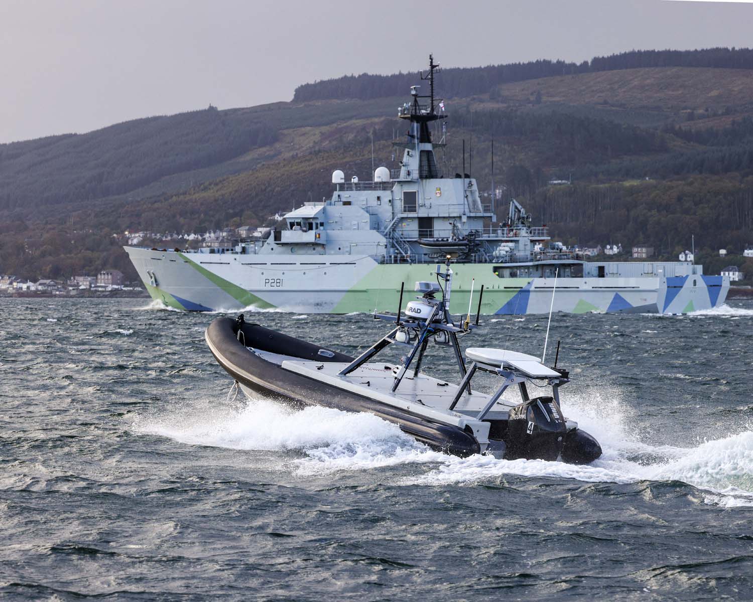 Autonomous Rattler boat operating alongside a Royal Navy warship during open-sea trials off the coast of Scotland