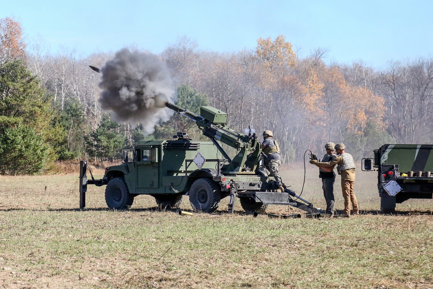 Soldiers firing a HUMVEE Hawkeye 105-millimeter soft recoil mobile howitzer