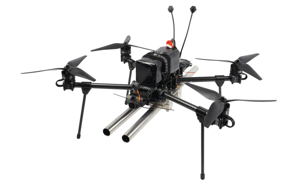 Fully assembled black quadcopter drone carrying a twin-barreled shotgun payload on a white background.