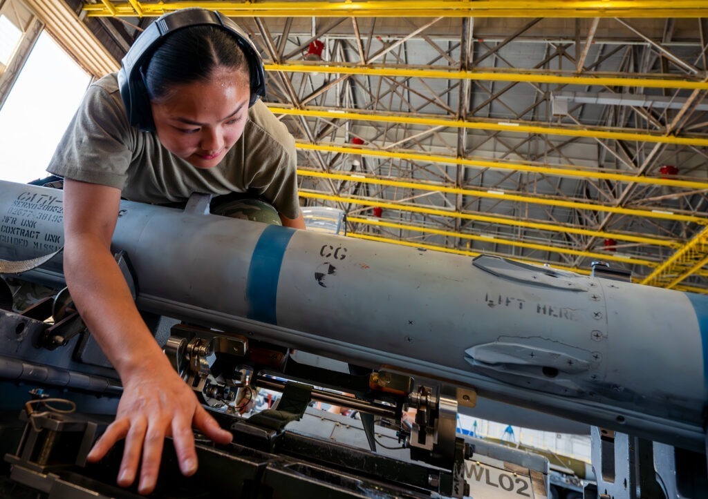 A GBU-38 being secured by a female Air Force staff sergeant before moving it during the unit’s quarterly weapons load competition