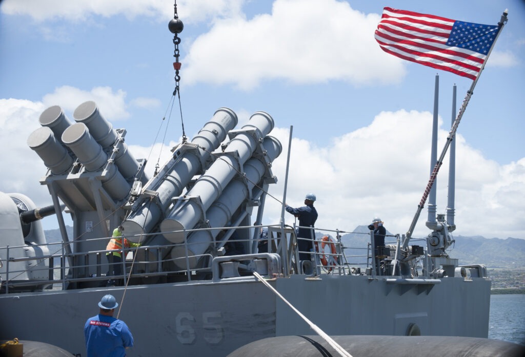 U.S. Navy Sailors and BAE Systems personnel work together to load a Harpoon missile (RGM 84) onto the Ticonderoga-class guided-missile cruiser USS Chosin (CG 65)