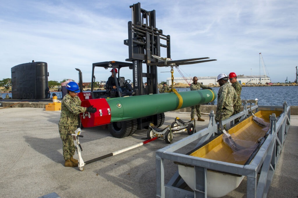 Sailors assigned to the Emory S. Land-class submarine tender USS Frank Cable (AS 40) remove a UGM-84 Harpoon anti-ship cruise missile on the pier onboard Naval Base Guam