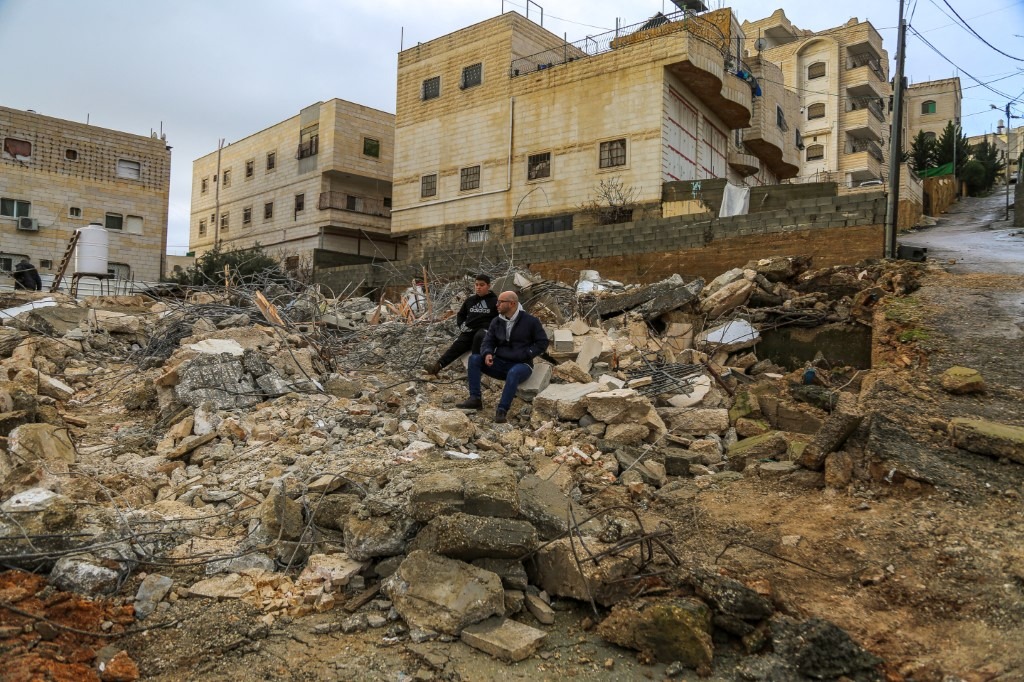 A man and a boy sit in the rubble of the home of the family of Imran al-Atrash, demolished by Israeli forces during a raid in Hebron’s Khallat Nafisa area in West Bank