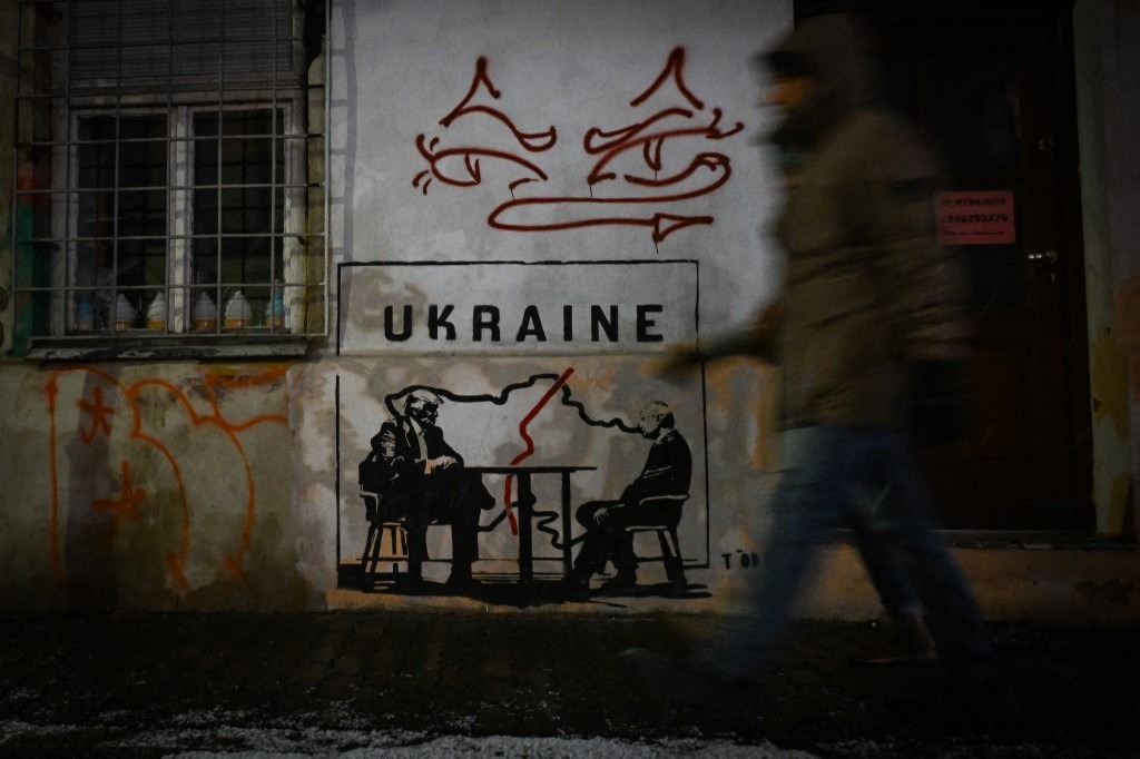 A mural titled 'Divided by Oligarchy' by anonymous Norwegian street artist Toddel, depicting US President Donald Trump and Russian President Vladimir Putin seated at a table next to a map of a divided Ukraine, is seen on a wall in Krakow, Poland, on January 29, 2026.