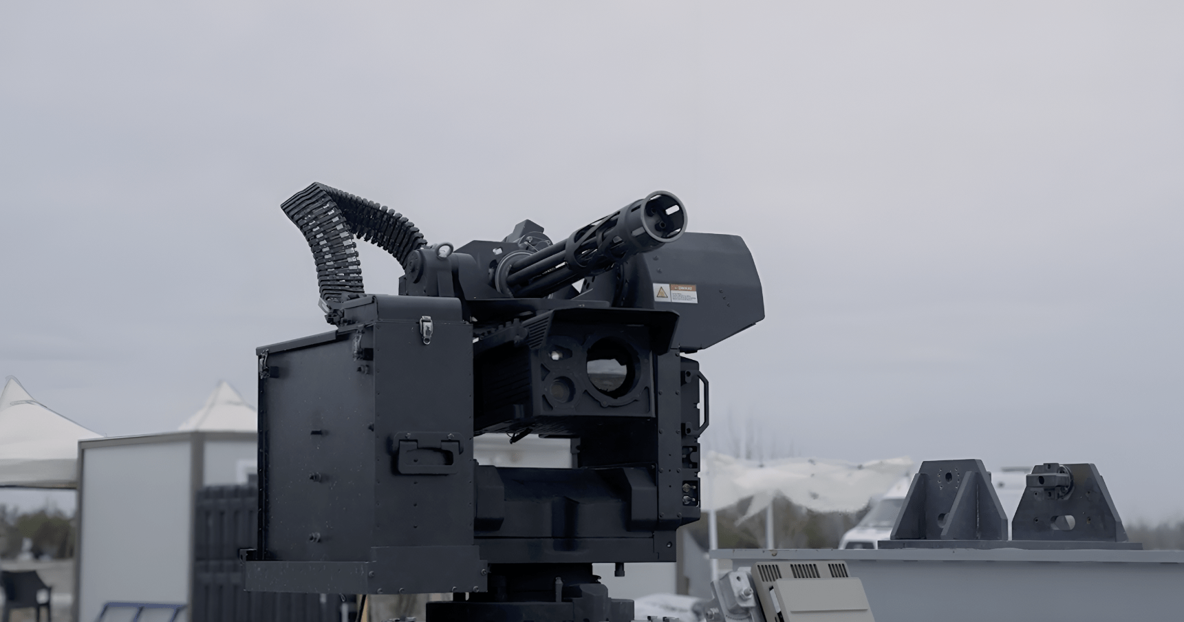 Remote-controlled counter-drone system displayed in Turkey, featuring a stabilized mount, ammunition feed, and multi-barrel cannon during an outdoor defense exhibition.