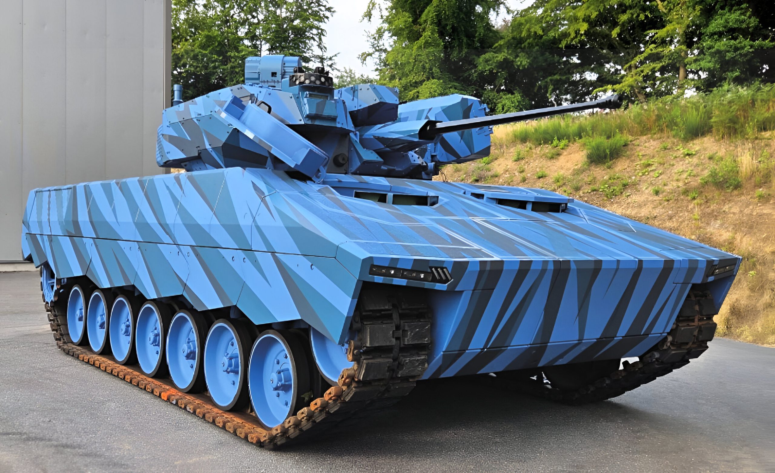 Condor tank on display, a modern tracked armored vehicle with angular blue camouflage, turret-mounted cannon, and multiple road wheels, parked outdoors near a facility