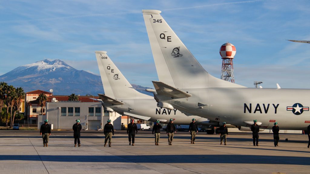 Sailors conduct a foreign object debris (FOD) walkdown on the flight line to ensure a safe operating environment for aircraft, including the P-8 Poseidon