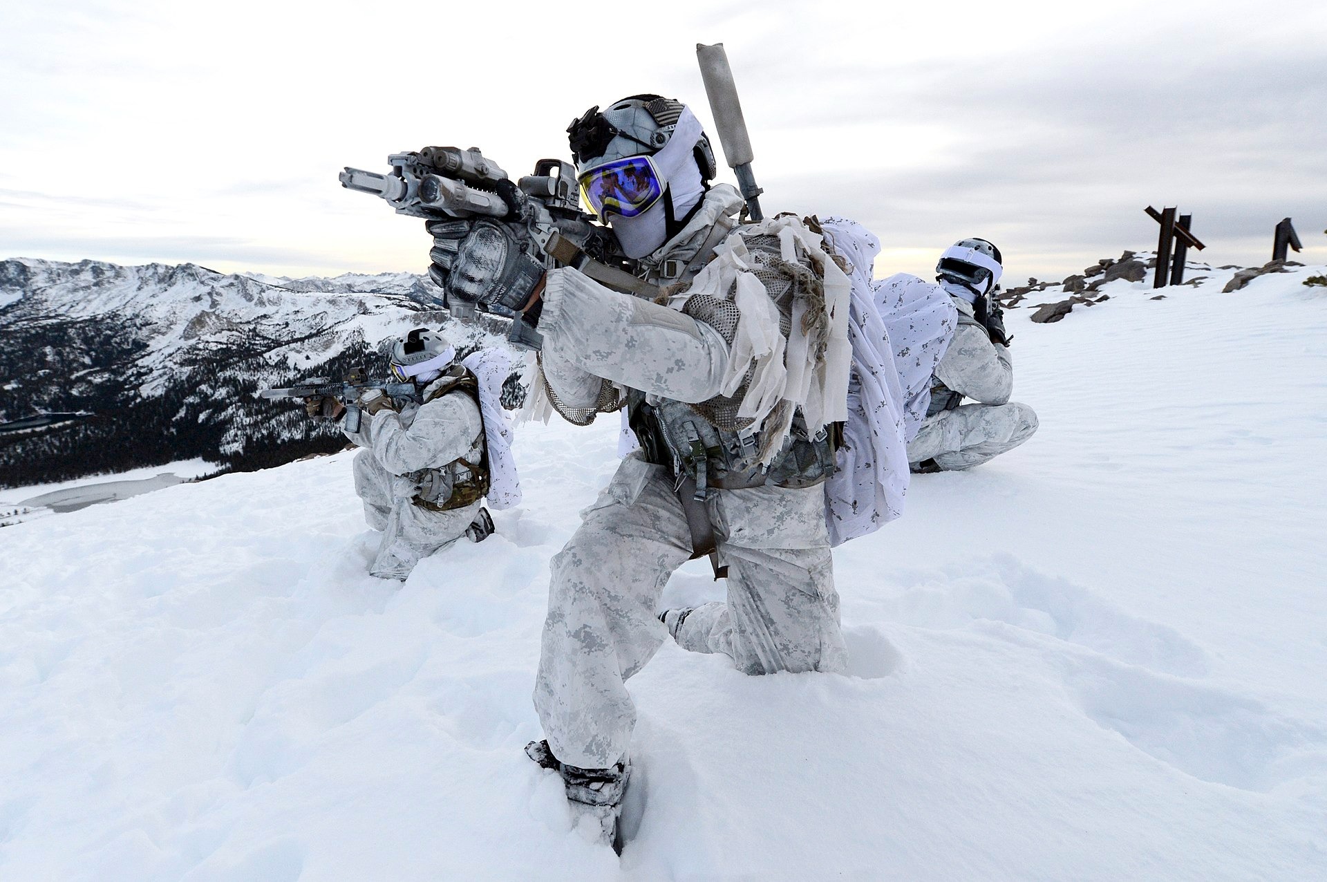 US Navy SEALs in winter warfare gear conducting tactical training in an Arctic environment, featuring Future Assault Shell Technology (FAST) helmets and specialized arctic combat equipment.