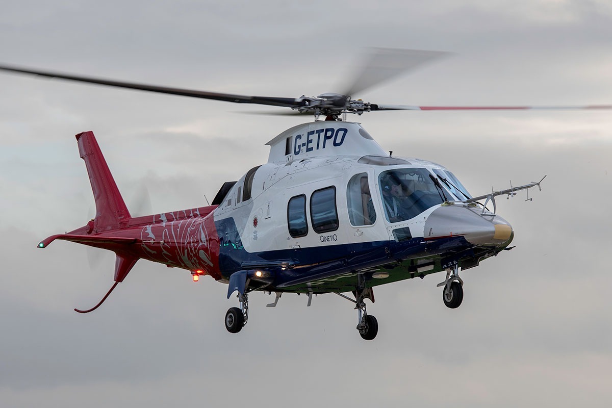 A QinetiQ helicopter in flight, featuring a critical component manufactured via 3D printing from recycled aircraft scrap metal.
