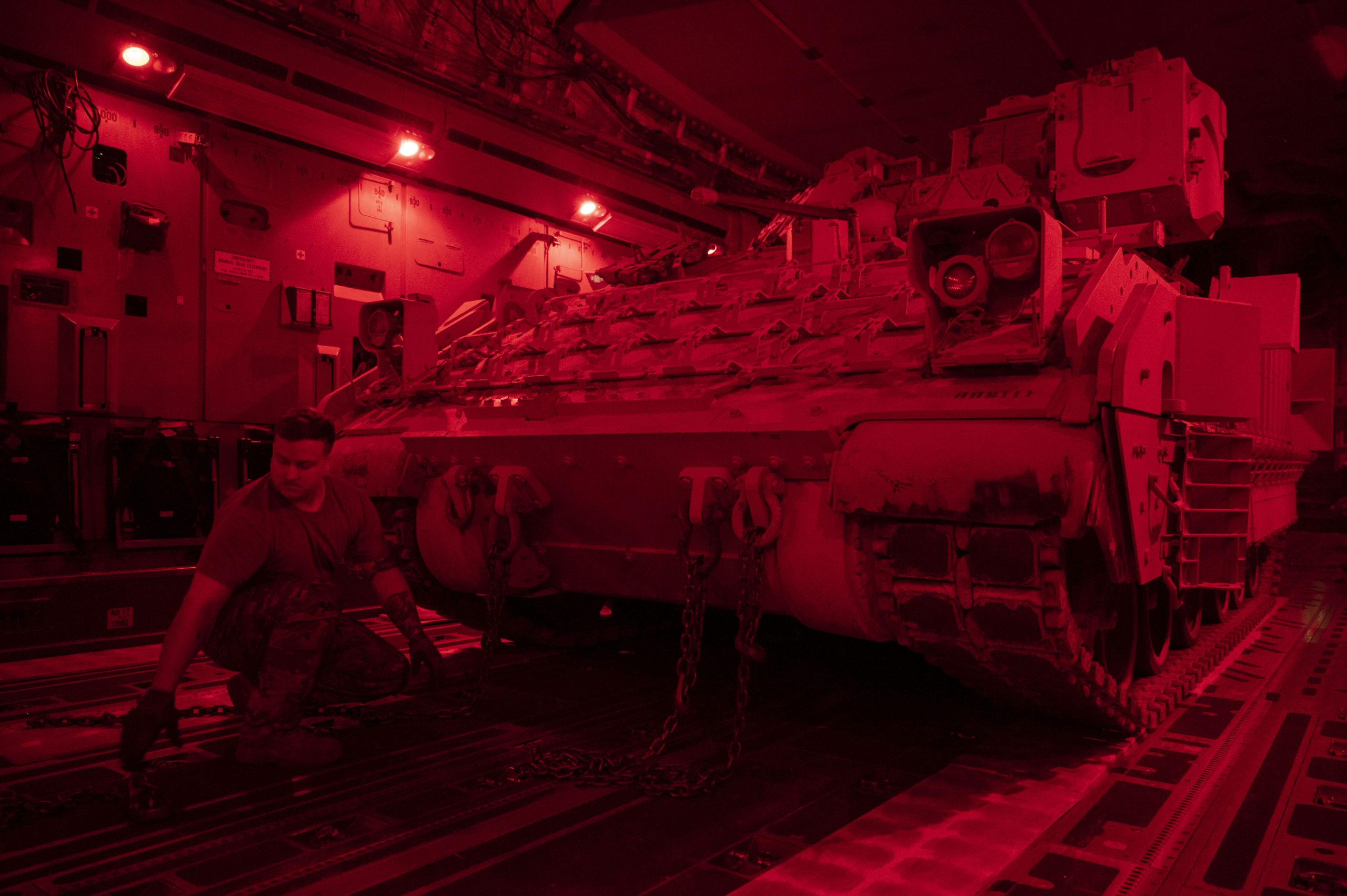 U.S. Air Force Staff Sgt. David Altman, 15th Expeditionary Airlift Squadron flying crew chief, secures a U.S. Army Bradley Fighting Vehicle onto a C-17 Globemaster III at an undisclosed location, Southwest Asia, June 29, 2023. U.S. Air Forces Central uses the Globemaster III to support partners with a rapidly deployable airlift asset for combat operations across austere airfields to deter regional aggressors and to assure regional regional partners in the area of responsibility. (U.S. Air Force photo by Staff Sgt. Emily Farnsworth)