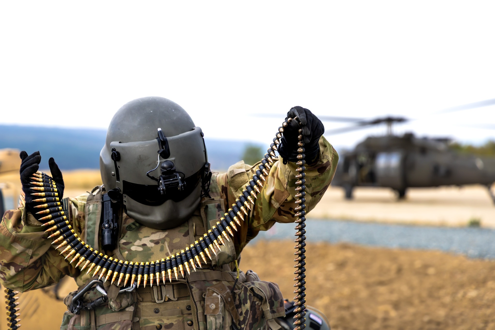 A U.S. Army Soldier, assigned to 3-501st Assault Helicopter Battalion, Combat Aviation Brigade, 1st Armored Division, prepares 7.62mm ammunition for an aerial gunnery exercise from a UH-60 Black Hawk helicopter at Novo Selo Training Area, Bulgaria on Aug. 23, 2025. 1AD CAB’s aerial gunnery increased lethality and proficiency of all Task Force Iron aviation crews on collective tables while generating warfighting readiness and combat credible forces along NATO’s Eastern Flank. (U.S. Army photo by Capt. Regina Koesters)