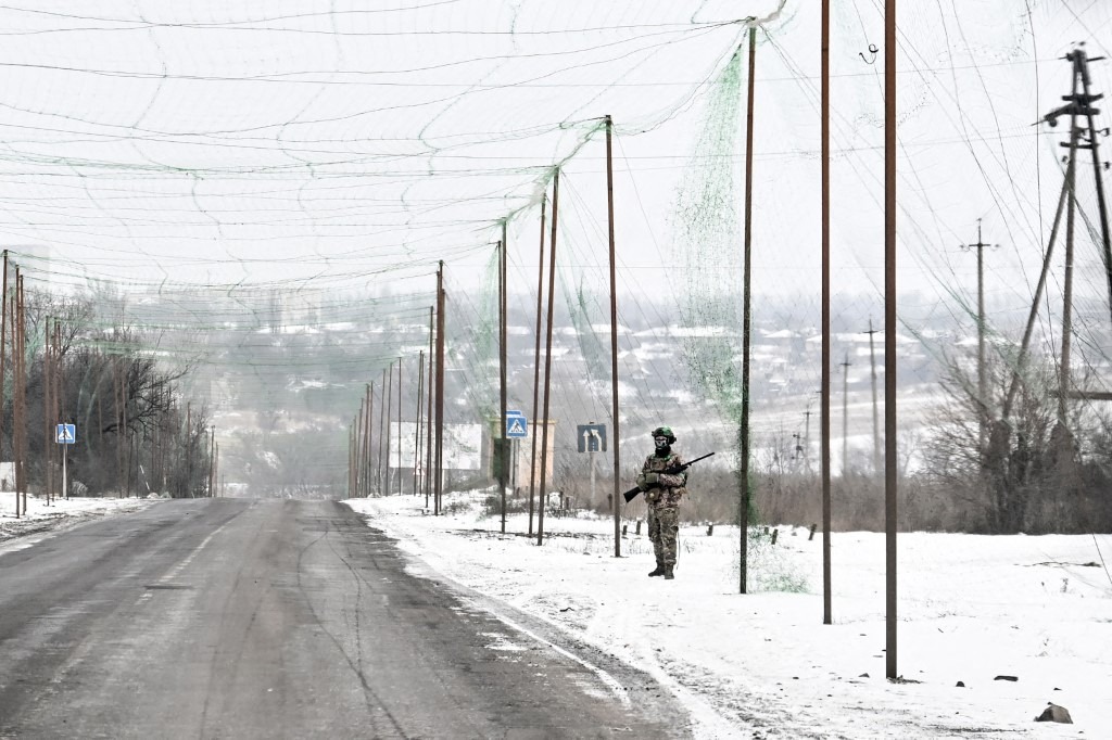 A soldier armed with a rifle stands on the roadside under an anti-drone net covering the road to protect from Russian FPV drone strikes in the Donetsk region, Ukraine, on January 23, 2026.