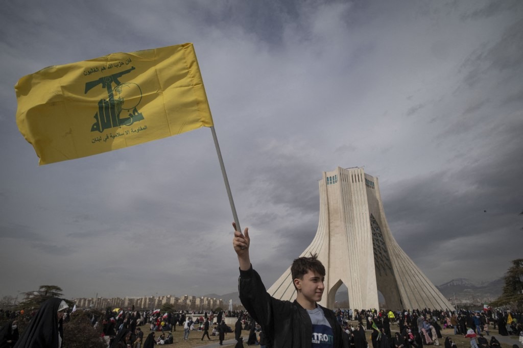 A young Iranian man waves a flag of Lebanon's Hezbollah while standing in front of the Azadi (freedom) monument during a rally commemorating the 47th anniversary of the Islamic Revolution's victory in Tehran, Iran, on February 11, 2026.