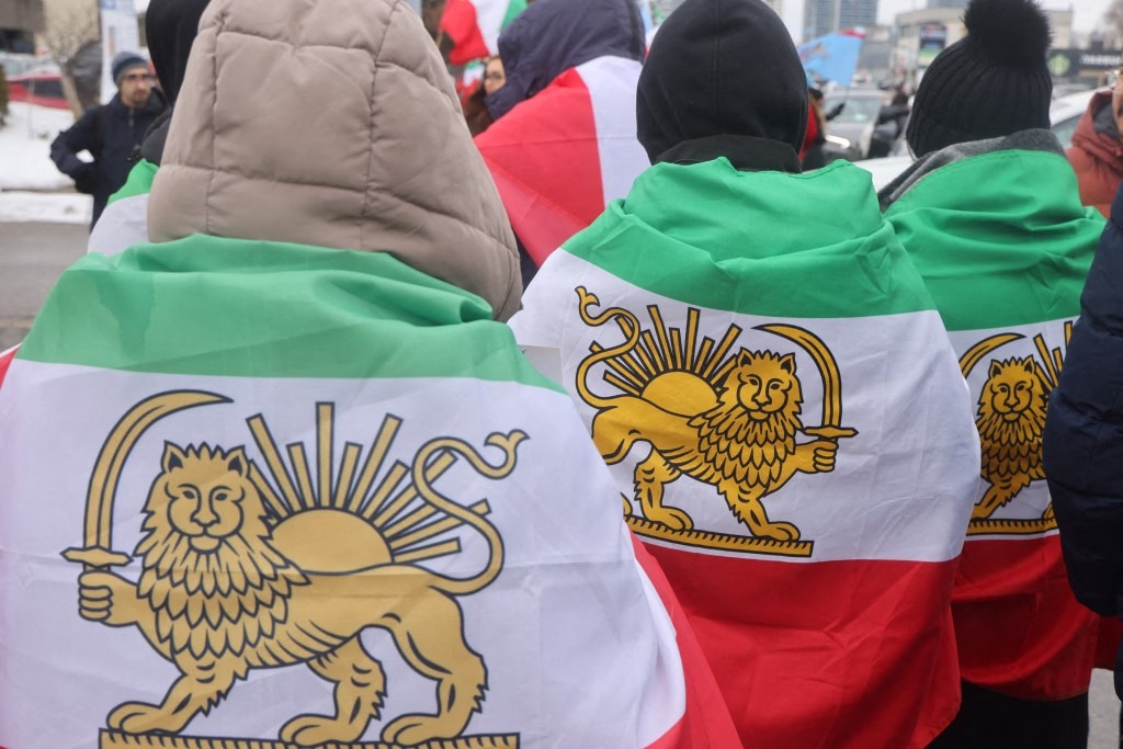 Protesters drape themselves in Iranian flags as 350,000 Canadians take part in a protest against the Islamic Republic of Iran in Toronto, Ontario, Canada, on February 14, 2026.